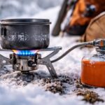 Kuchenka gazowa używana zimą na śniegu, palnik z niebieskim płomieniem i kartusz gazowy w mroźnych warunkach biwakowych